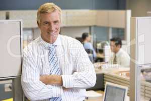 Businessman standing in cubicle smiling