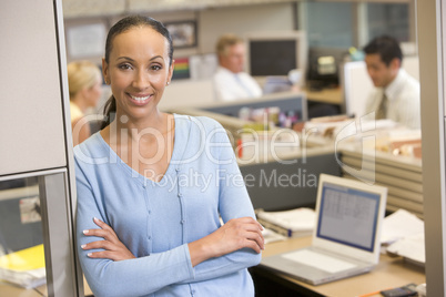 Businesswoman standing in cubicle smiling