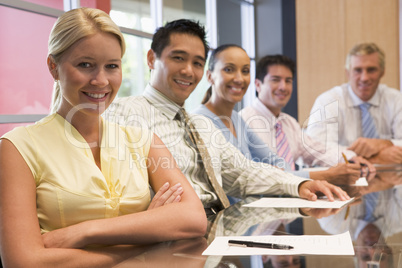 Five businesspeople at boardroom table smiling