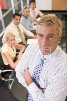 Businessman with four businesspeople at boardroom table in backg