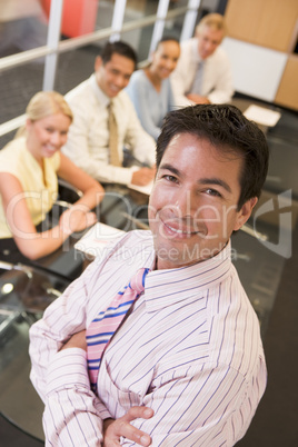 Businessman with four businesspeople at boardroom table in backg