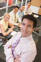 Businessman with four businesspeople at boardroom table in backg
