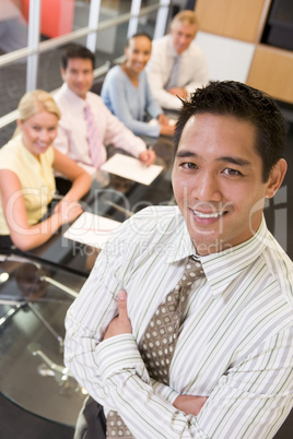 Businessman with four businesspeople at boardroom table in backg