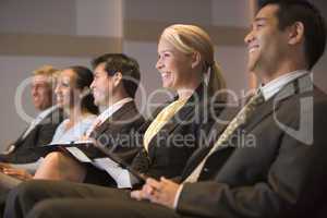 Five businesspeople smiling in presentation room with clipboards