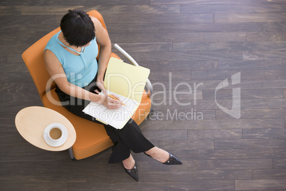 Businesswoman sitting indoors with coffee and folder