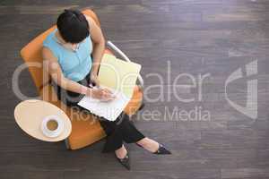Businesswoman sitting indoors with coffee and folder