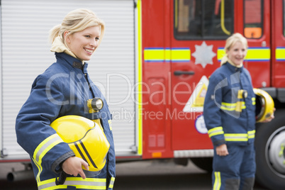 Zwei Feuerwehrfrauen sttehen vor einem Löschfahrzeug