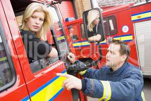 Eine Feuerwehrfrau unterhält sich aus einem Feuerwehrfahrzeug heruas mit einem Kollegen
