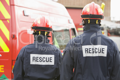 Zwei Feuerwehrmänner stehen  vor einem Feuerwehrfahrzeug