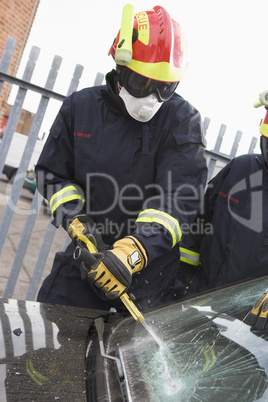 Ein Feuerwehrmann versucht das Fenster eines Unfallautos zu entfernen
