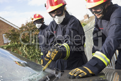 Zwei Feuerwehrmänner versuchen das Fenster eines Unfallautos zu entfernen