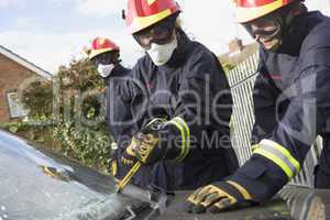 Zwei Feuerwehrmänner versuchen das Fenster eines Unfallautos zu entfernen