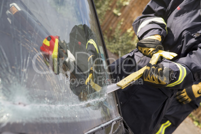 Ein Feuerwehrmann versucht das Fenster eines Unfallautos aufzuschneiden