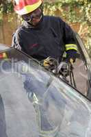 Ein Feuerwehrmann versucht das Fenster eines Unfallautos aufzuschneiden