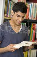 Male college student reading in a library