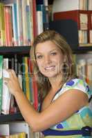 Female college student reaching for a library book
