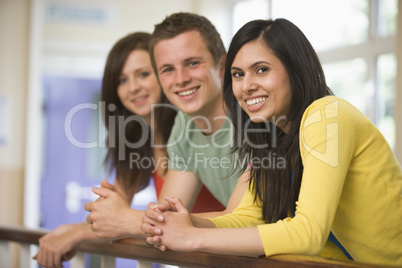 Three college students leaning on banister