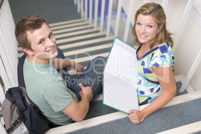 Male and female college students sitting on stairs