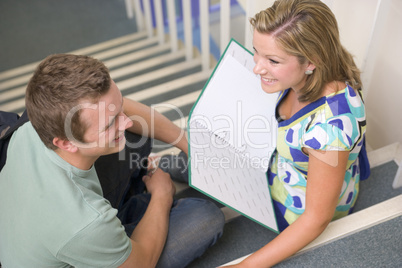 Male and female college students sitting on stairs