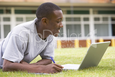College student using laptop on campus lawn