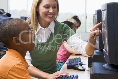 Teacher helping kindergarten children learn how to use computers