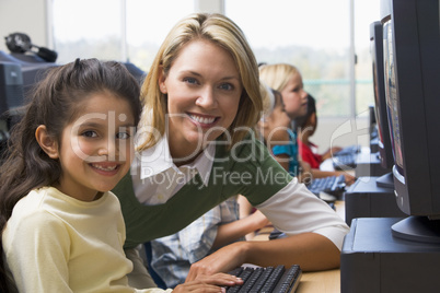 Teacher helping kindergarten children learn how to use computers