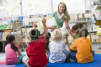 Kindergarten teacher reading to children in library