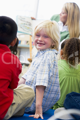 Kindergarten teacher reading to children in library, boy looking