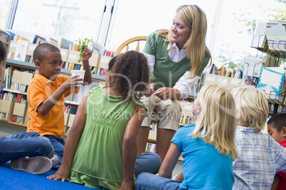 Kindergarten teacher and children looking at seedling in library