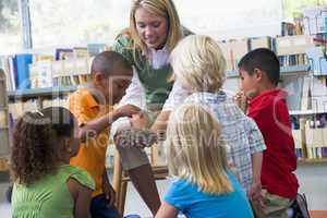 Kindergarten teacher and children looking at bird's nest in libr