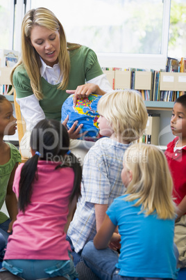 Kindergarten teacher and children looking at globe