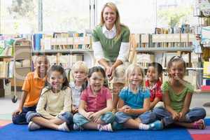 Kindergarten teacher sitting with children in library