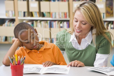 Kindergarten teacher helping student with reading skills