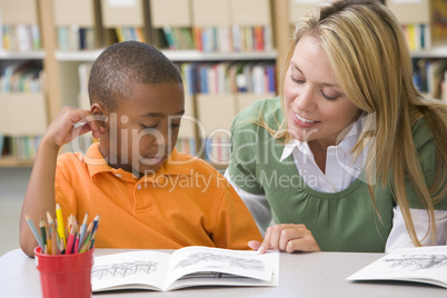 Kindergarten teacher helping student with reading skills