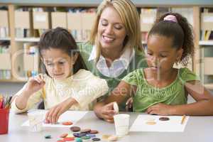 Kindergarten teacher sitting with students in art class,