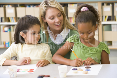 Kindergarten teacher sitting with students in art class