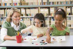 Kindergarten teacher sitting with students in art class