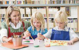 Kindergarten teacher sitting with students in art class