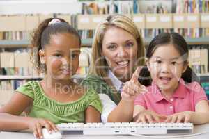 Kindergarten teacher sitting with children at computer