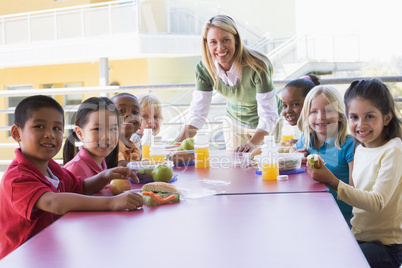 Kindergarten teacher supervising children eating lunch