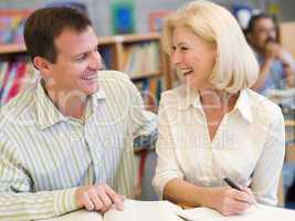 Mature student laughing with tutor in library