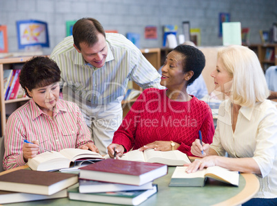 Teacher helping mature students in library