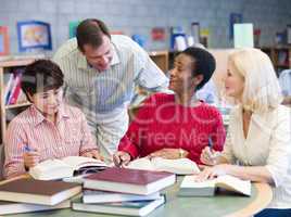 Teacher helping mature students in library