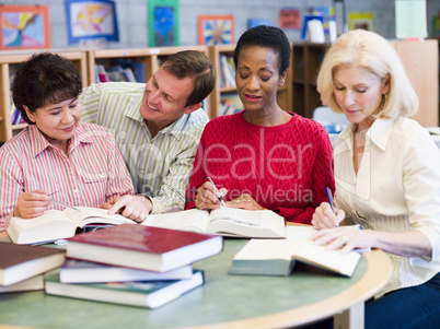 Teacher helping mature students in library