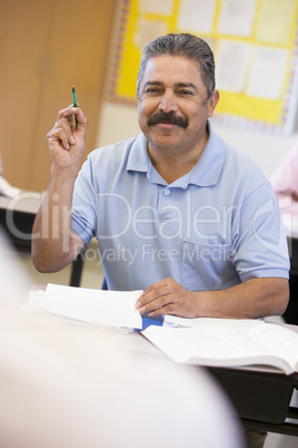 Mature male student raising hand in class