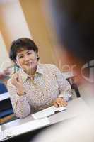 Mature female student raising hand in class