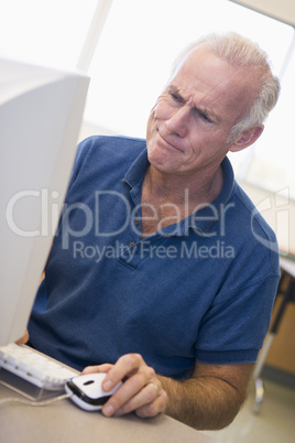 Mature male student frowning at computer monitor