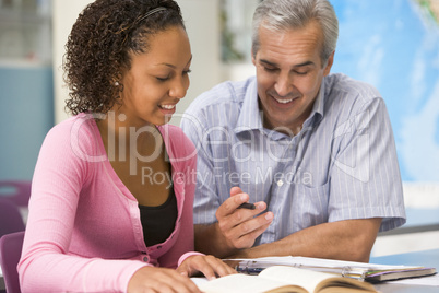 A teacher instructs a schoolgirl in a high school class