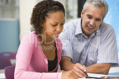 A teacher instructs a schoolgirl in a high school class