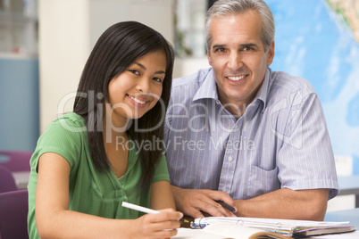 A teacher instructs a schoolgirl in a high school class